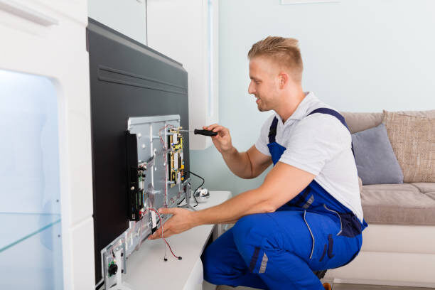 Young Male Electrician Repairing Television With Screwdriver